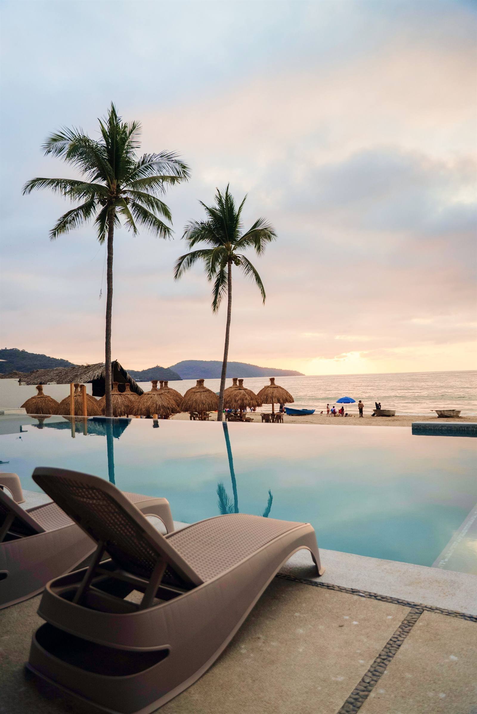 Avenir Armonia Suites: poolside loungers and palm trees facing the ocean at sunset